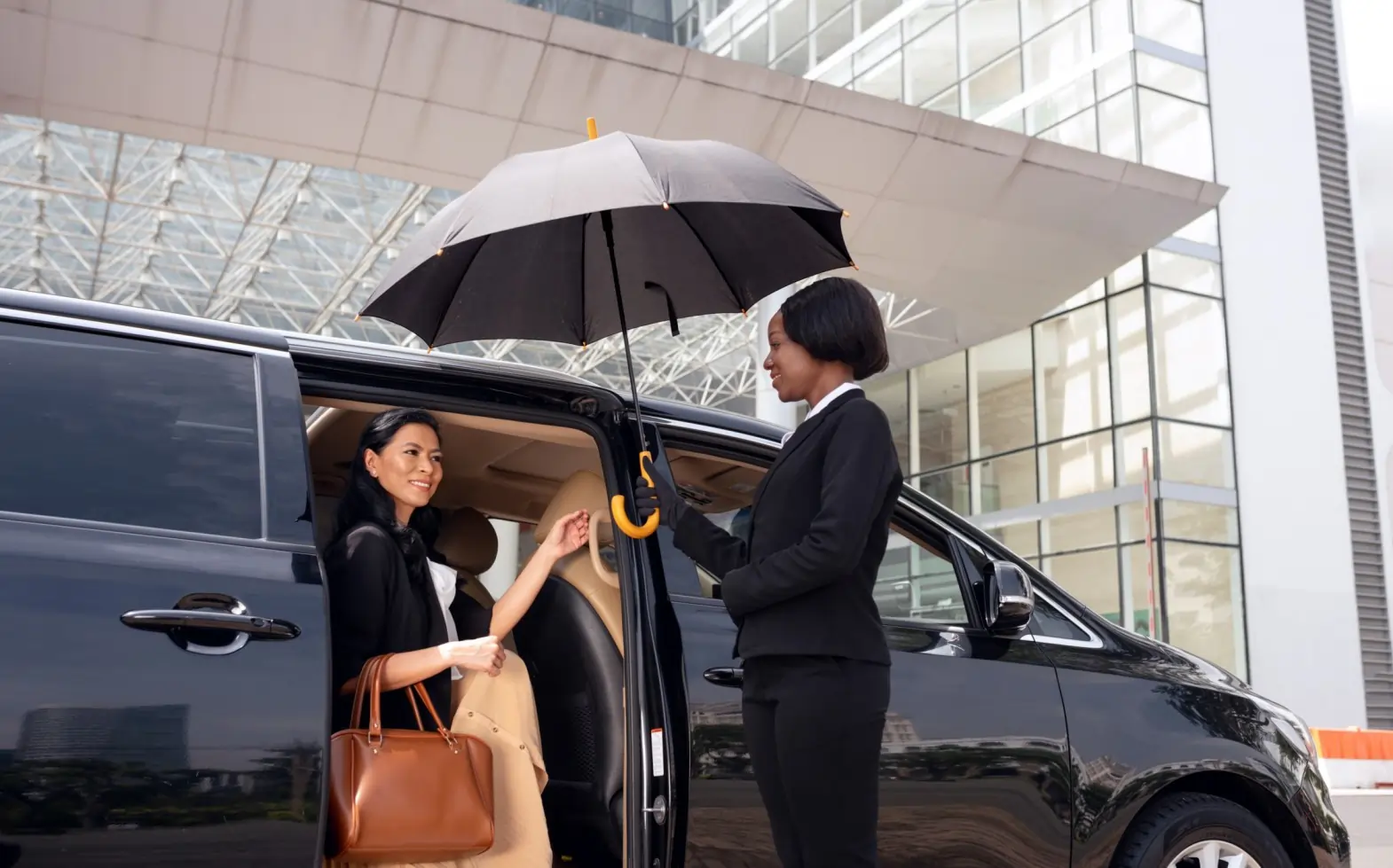 Professional chauffeur holding umbrella assisting businesswoman exiting luxury black vehicle for Bradford Limo Service Toronto Airport transfer.