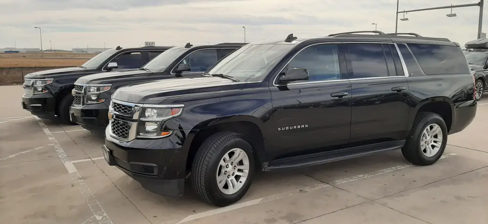 A row of black Chevrolet Suburban SUVs parked in a lot, with a premium limo fleet for Milton Limo Service in Ontario. The vehicles are lined up neatly, ready for airport or private transportation services.