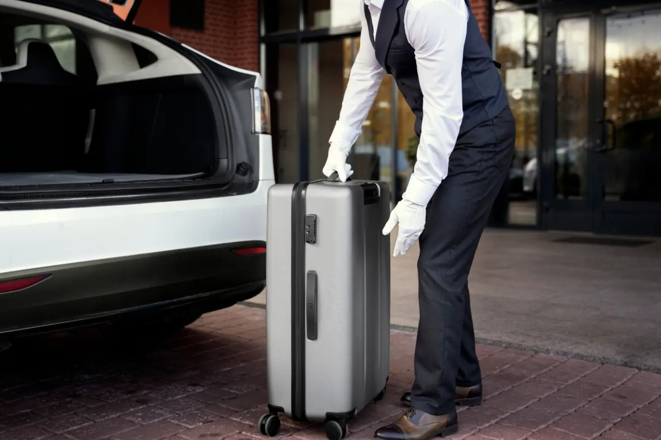 Professional chauffeur providing Billy Bishop Airport limo service while handling passenger luggage near a luxury vehicle