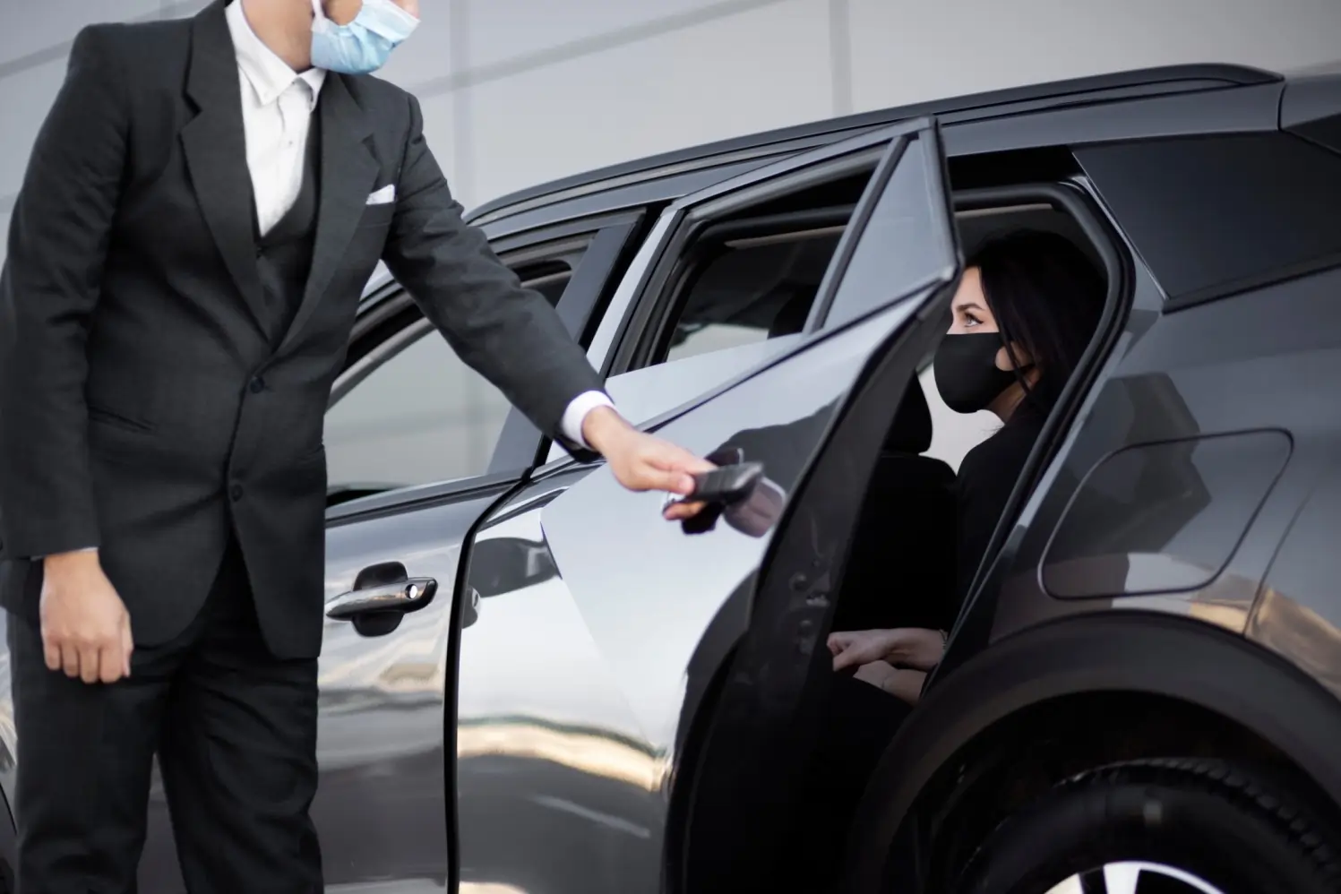 Professional masked chauffeur opening luxury vehicle door for arriving passenger, offering seamless Brantford to Toronto Pearson Airport limo transfer.